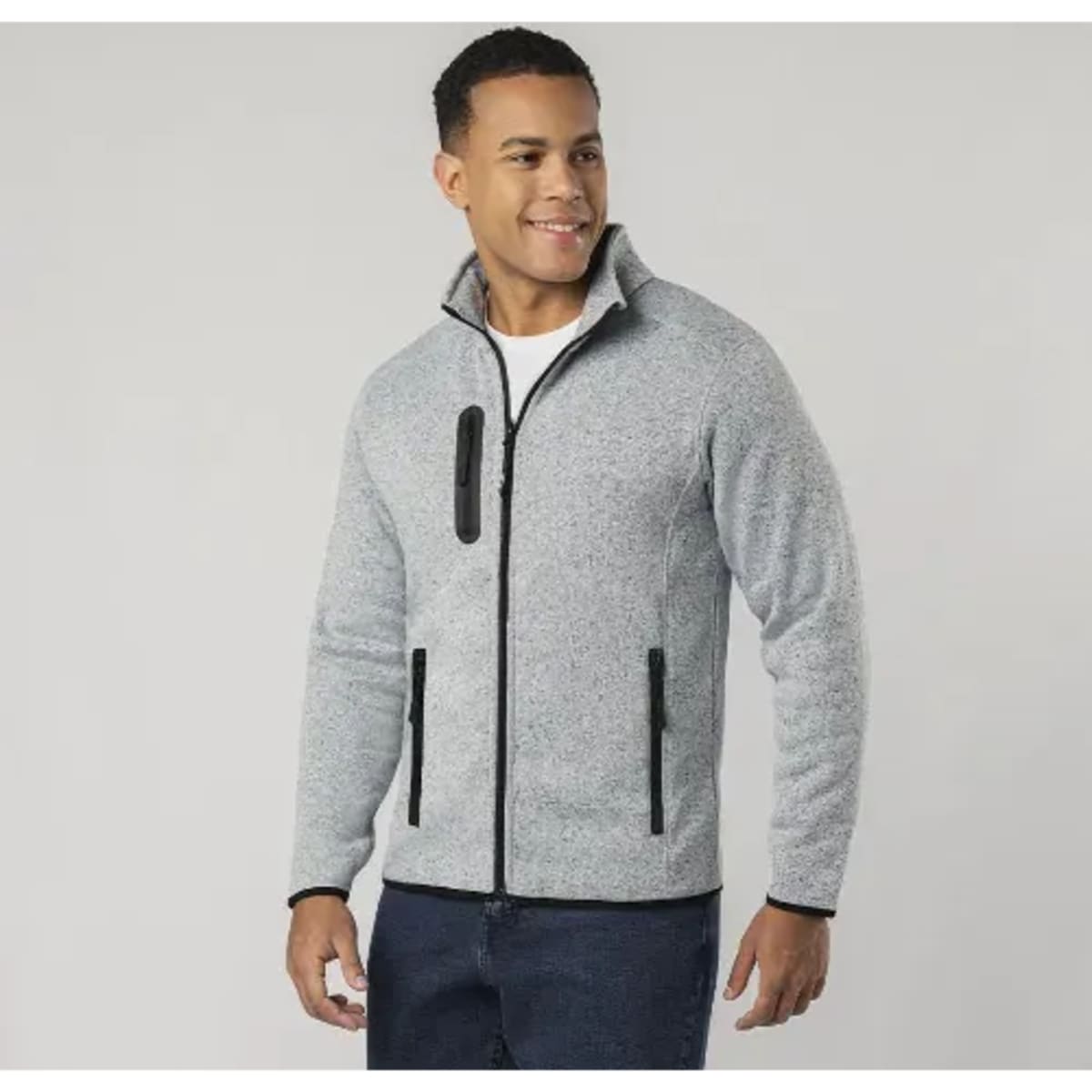 A polar fleece jacket in grey with black zip and pocket detailing, worn by a smiling model.