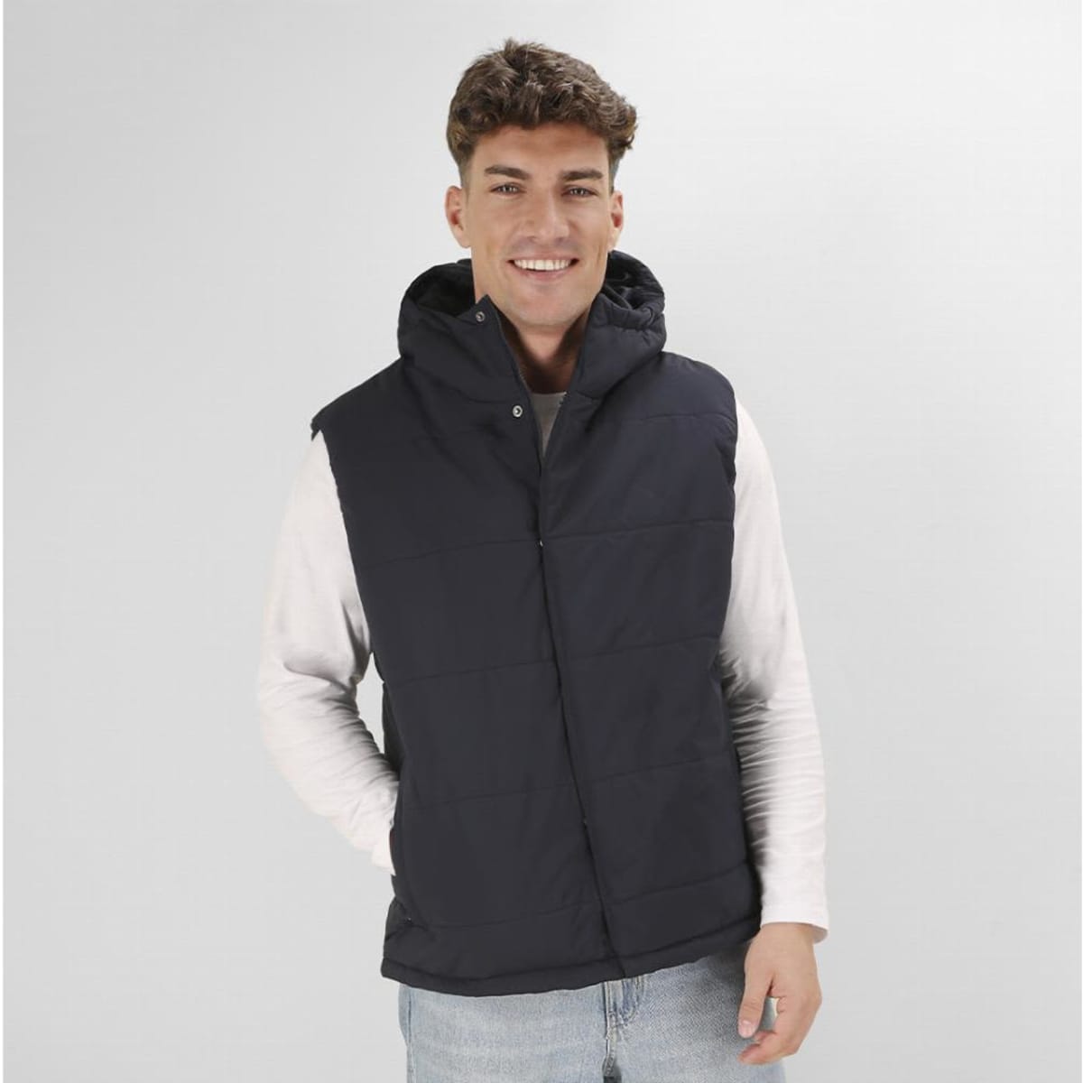 A man wearing a dark navy sleeveless puffer vest with a hood, paired with a light-coloured long-sleeve shirt.