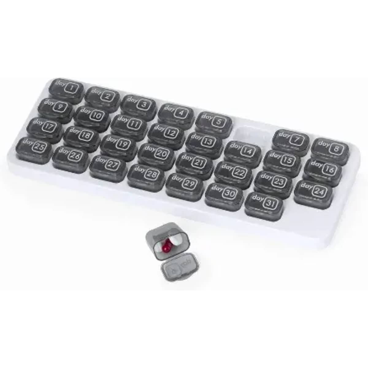 A grey and white pill organiser with compartments labelled for each day, featuring a small, red capsule beside it.