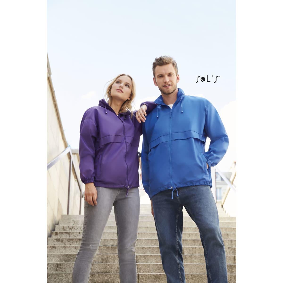 A purple and a blue unisex raincoat made of 100% waterproof nylon, featuring a hood and front pockets.