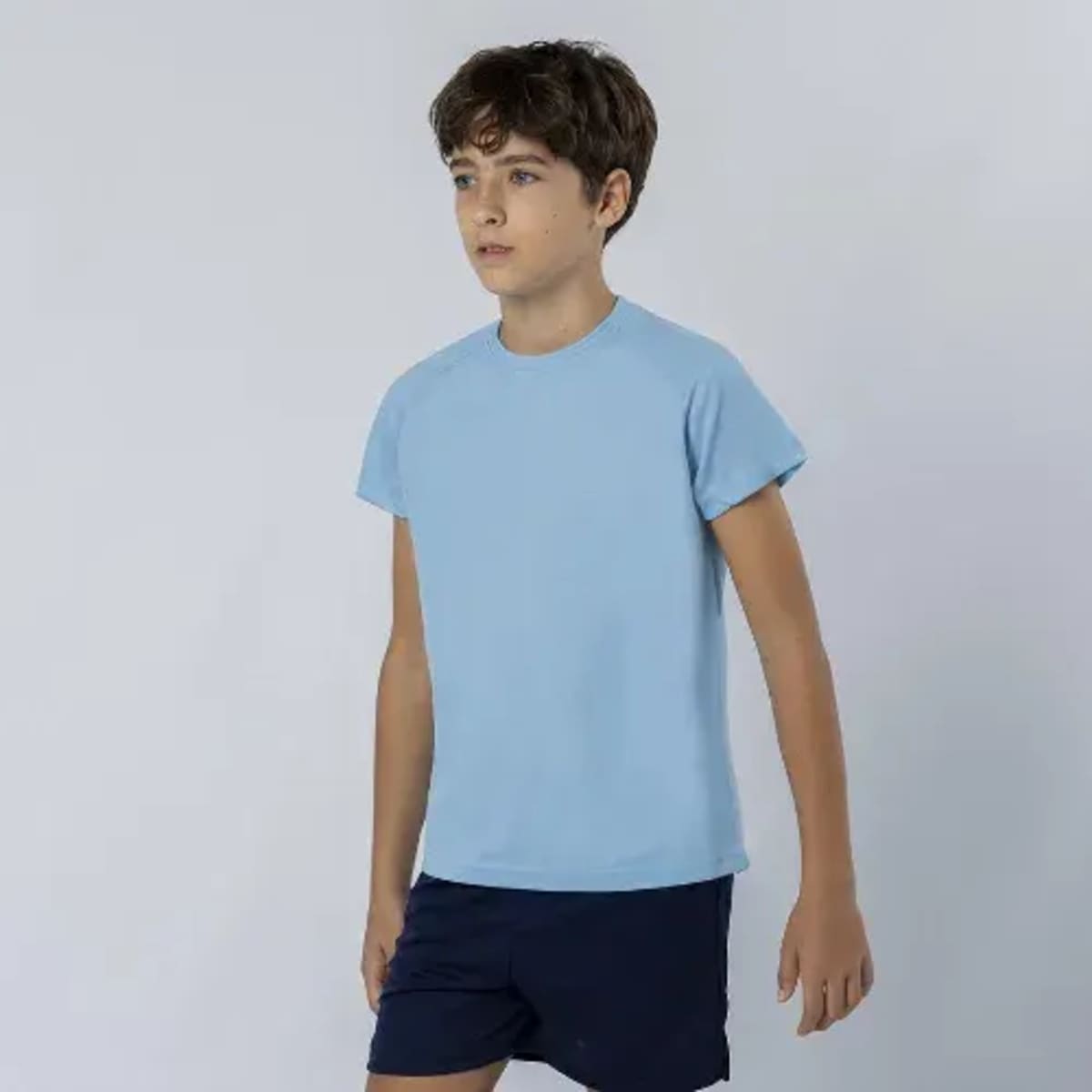A light blue kids' t-shirt with short sleeves, paired with navy shorts, featuring a logo.