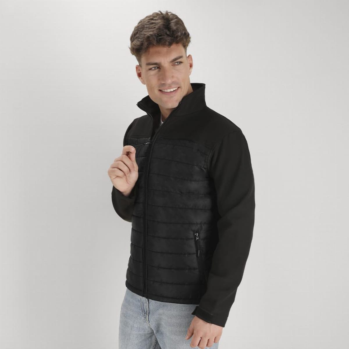 A man wearing a black jacket with a zippered front and pockets, set against a plain background.