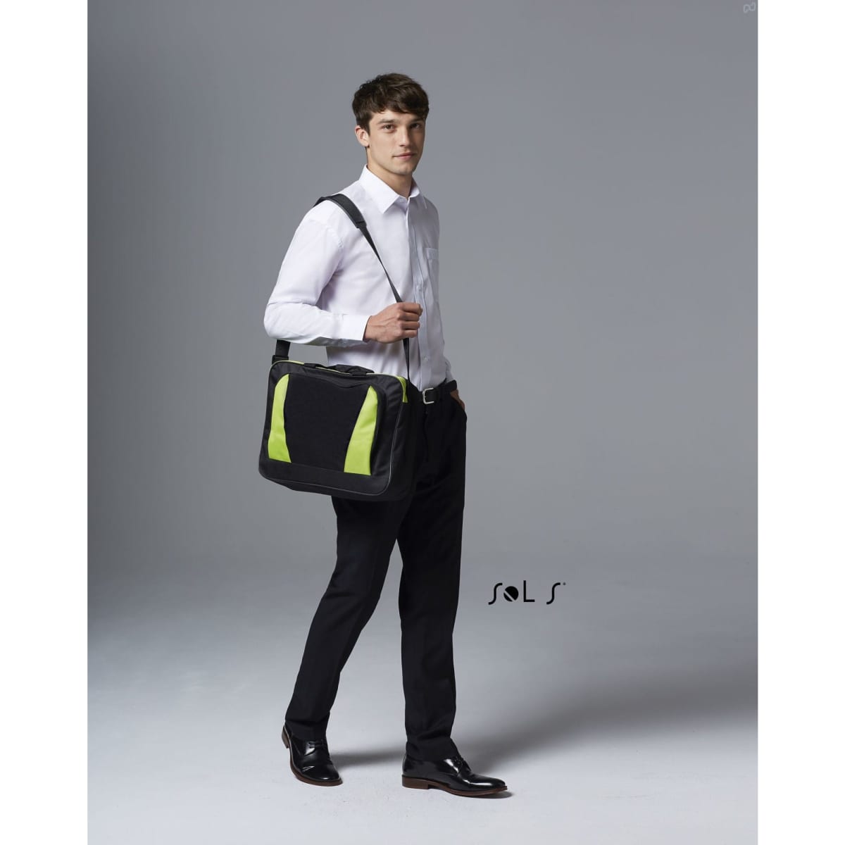 A black briefcase with green accents is held by a man in formal attire, standing against a neutral background.
