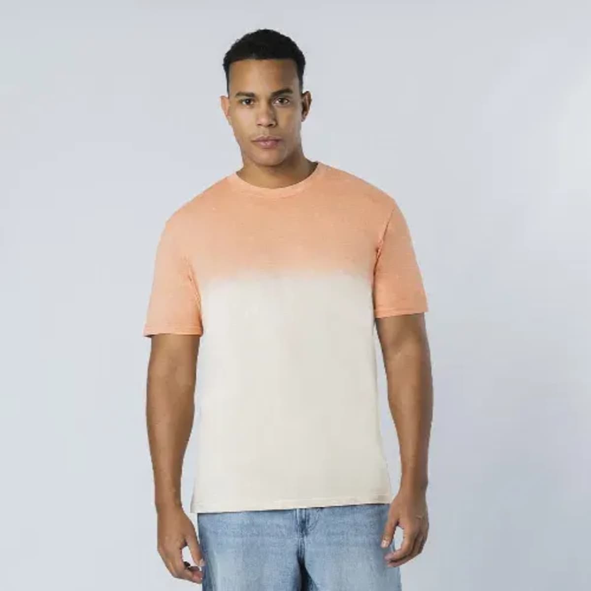 A T-shirt in a gradient of orange and cream tones, featuring short sleeves and a relaxed fit. It has a visible logo.