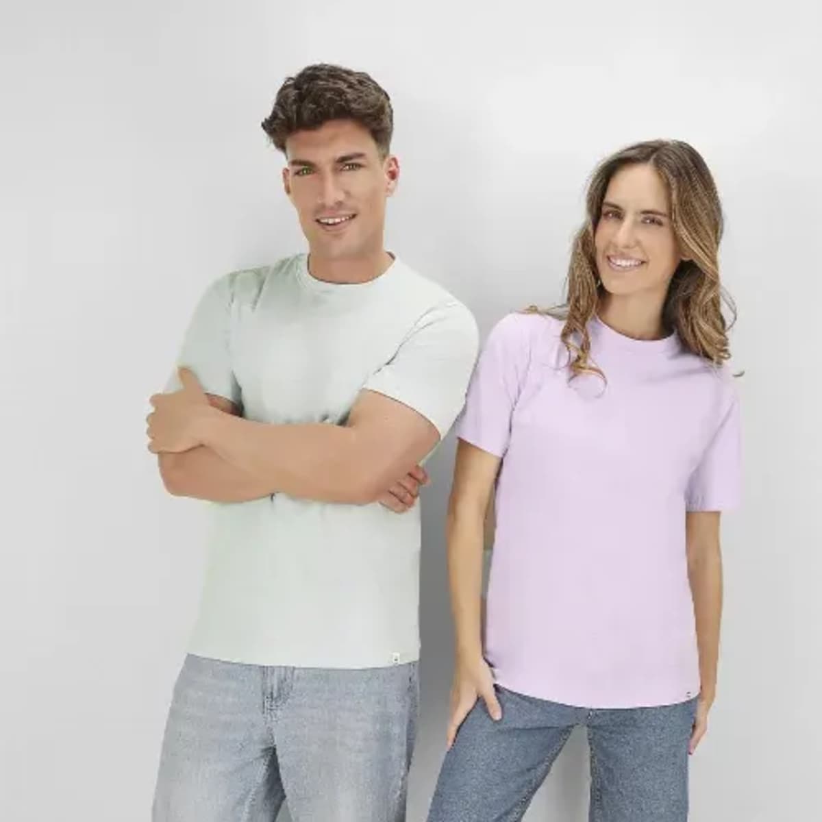 A mint green and a lilac T-shirt worn by a man and a woman, both smiling. Each shirt has a logo.