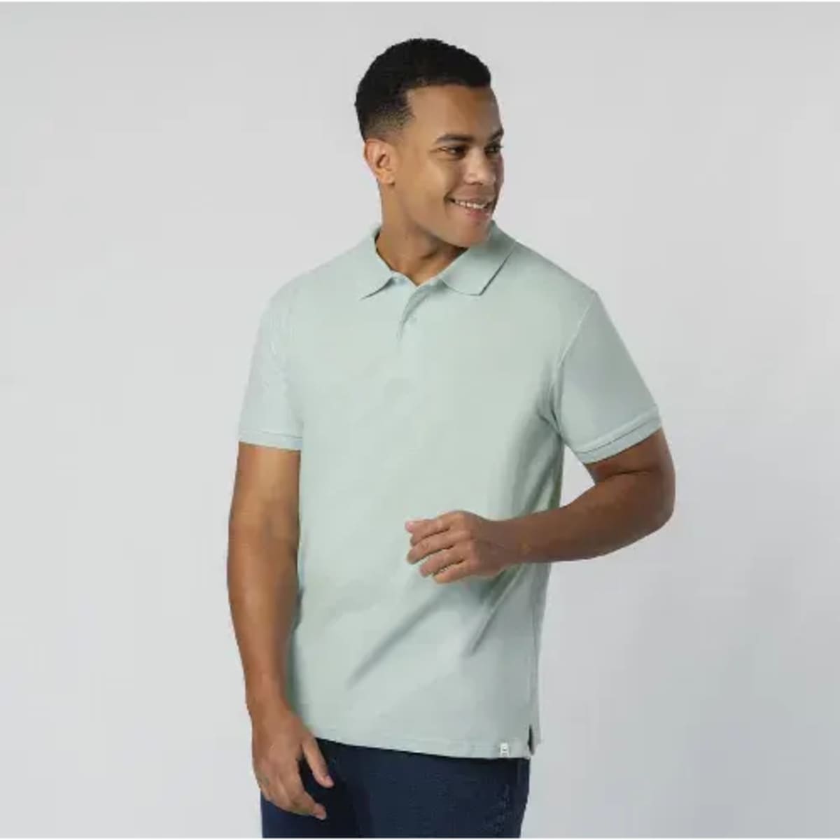 A light green adult polo shirt featuring a collar and short sleeves. The model is smiling while posing.