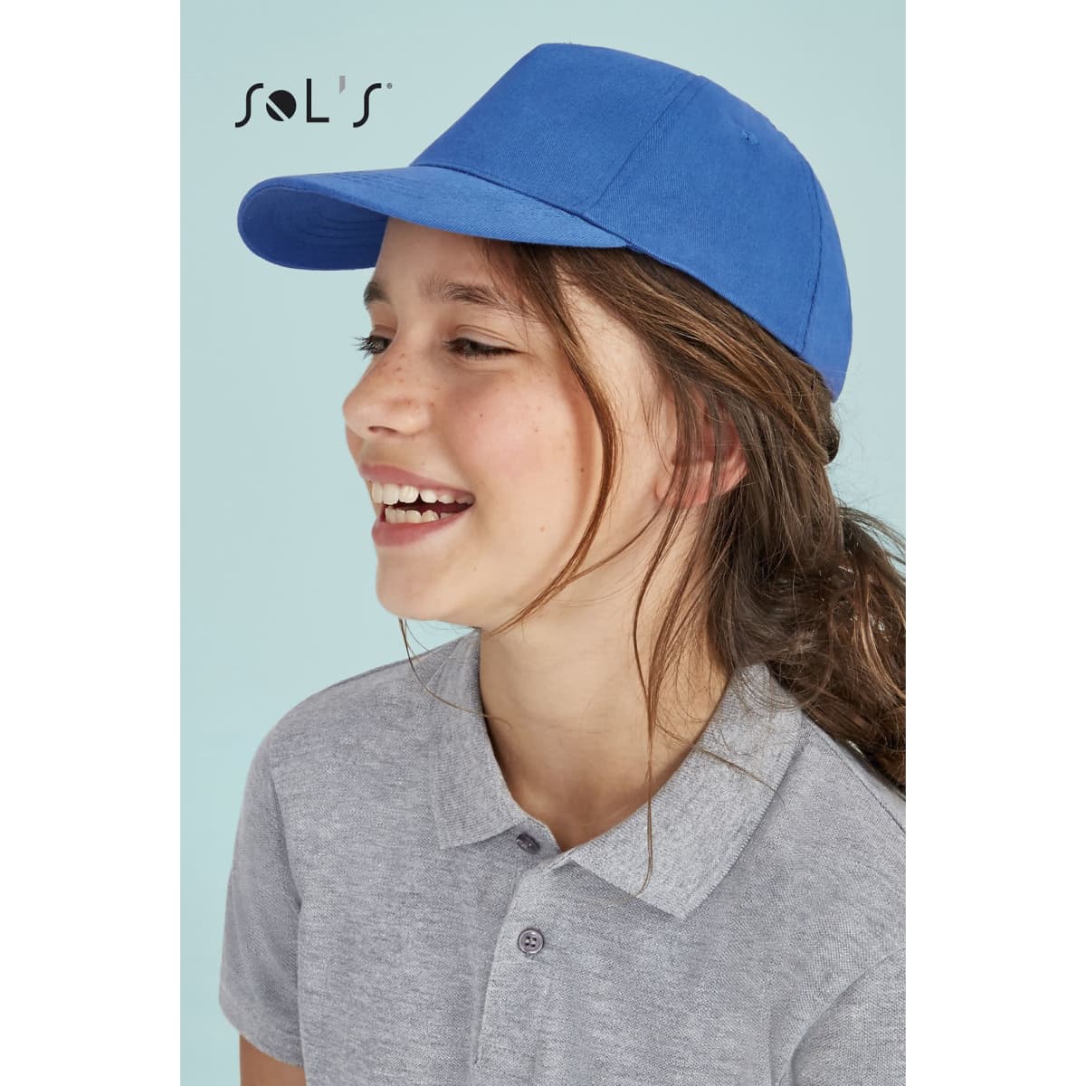 A blue five-panel cap made of light brushed cotton, worn by a smiling child. The cap features a logo.