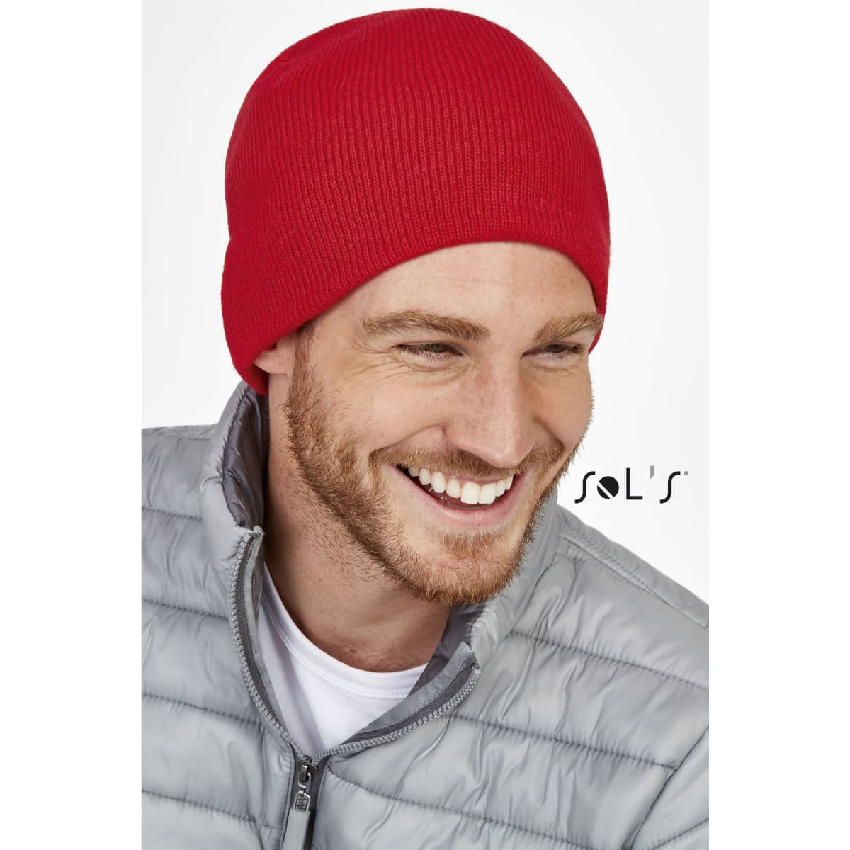 A red unisex acrylic beanie worn by a man, featuring a logo on the side.