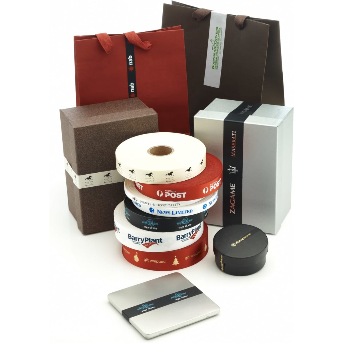Custom printed satin ribbon in various colours, displayed with gift boxes and shopping bags, some featuring logos.