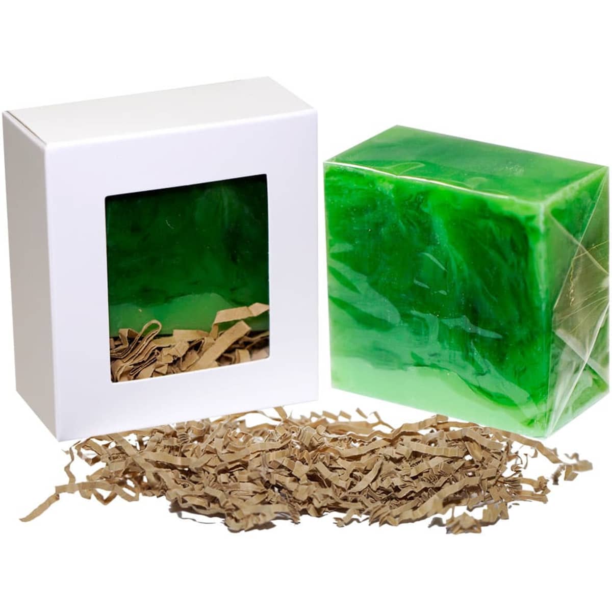 A green soap bar in clear packaging alongside a boxed display with shredded paper. The box features a window.
