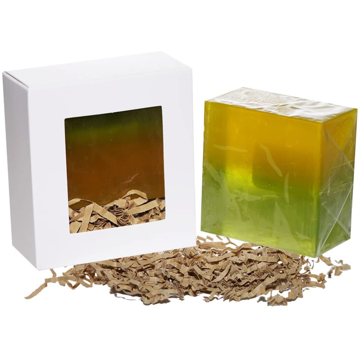 A transparent soap bar in green and yellow hues, placed next to a white box with a window and shredded paper inside.