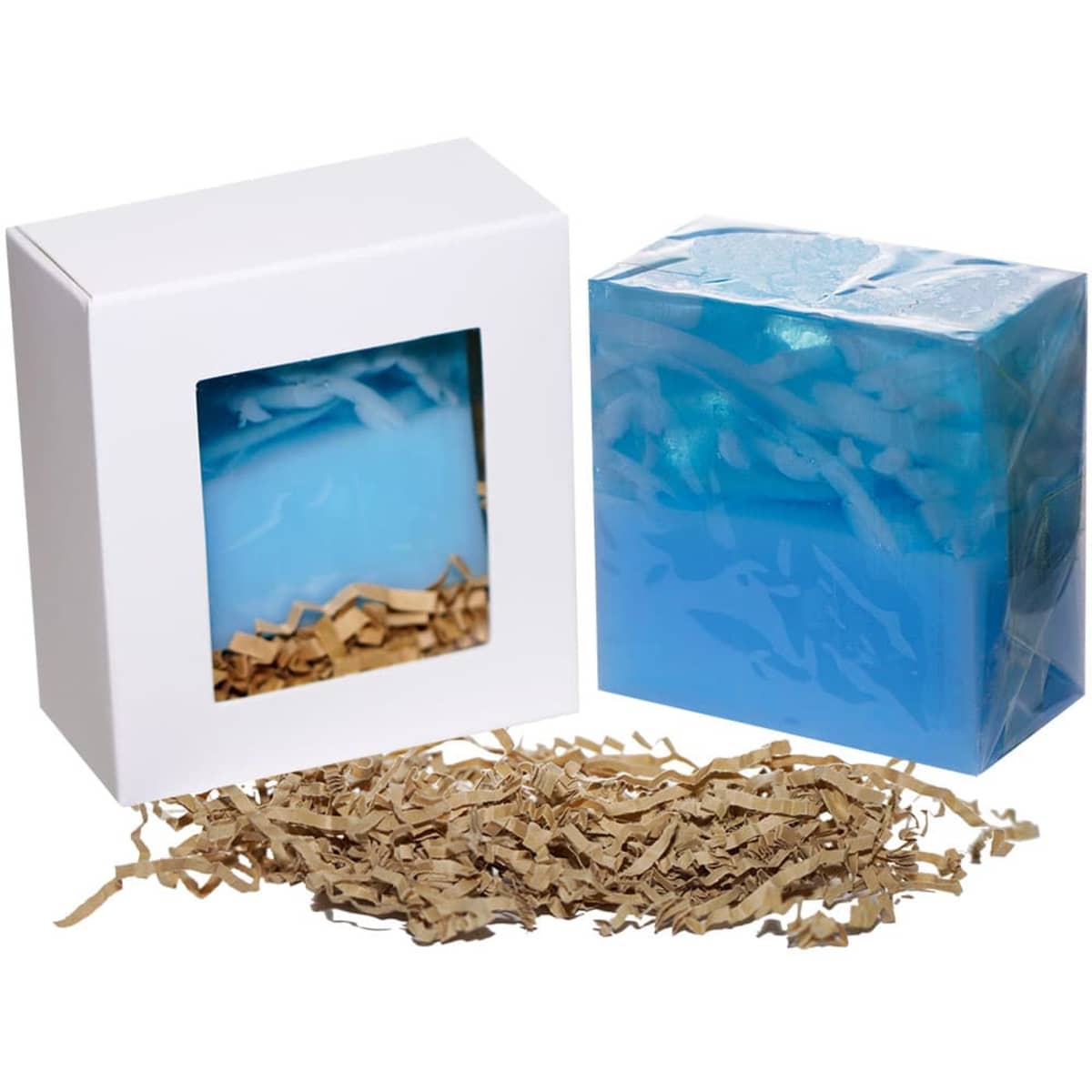 A blue soap bar packaged in a white box with a clear window, accompanied by shredded paper for cushioning.
