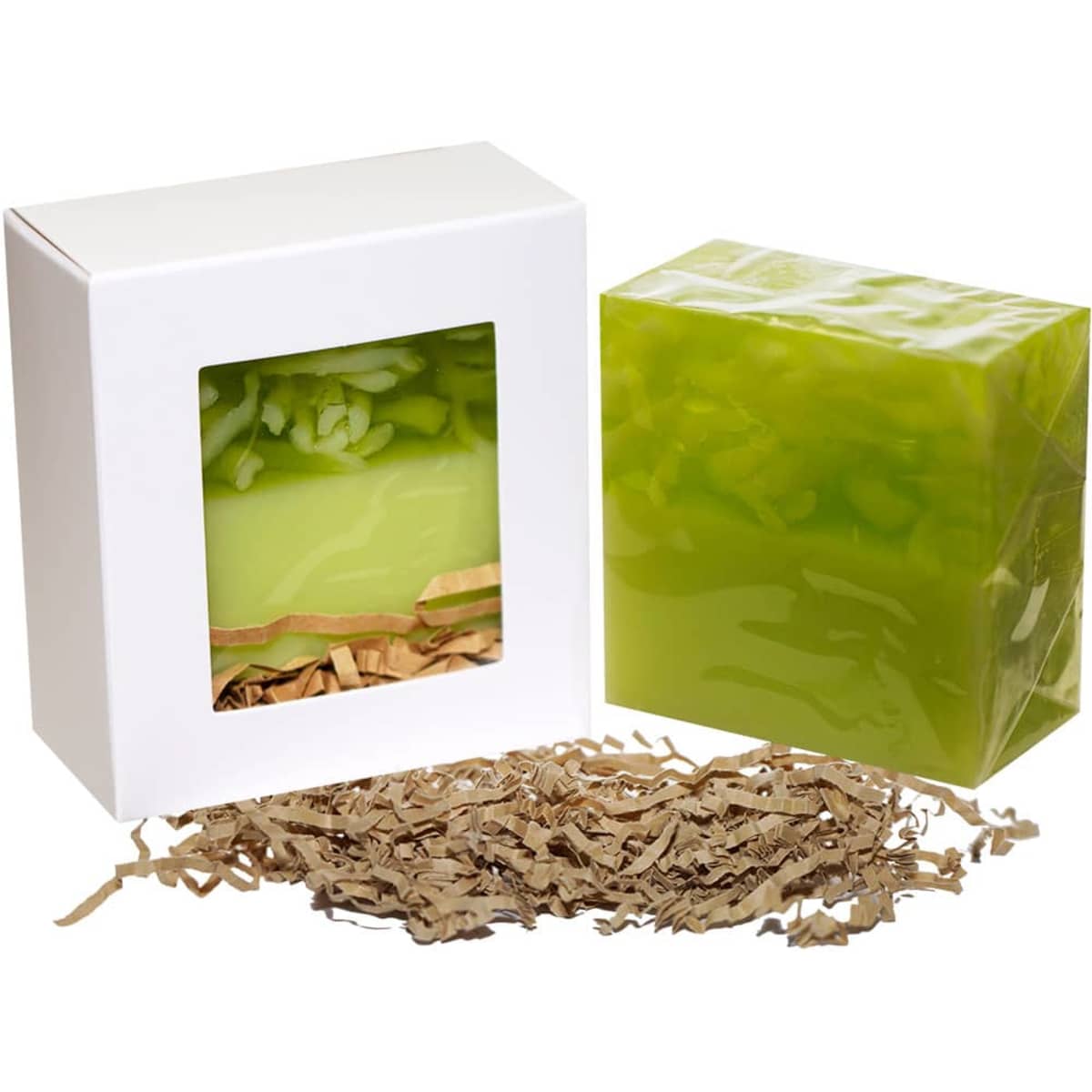 A green soap bar in a box with a window, accompanied by shredded brown packaging material. The box has a logo.