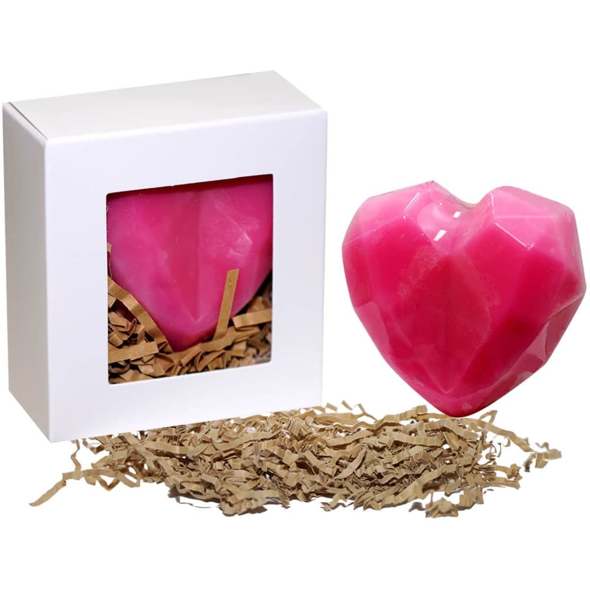 A heart-shaped pink soap presented in a white box, with shredded paper inside and around it.