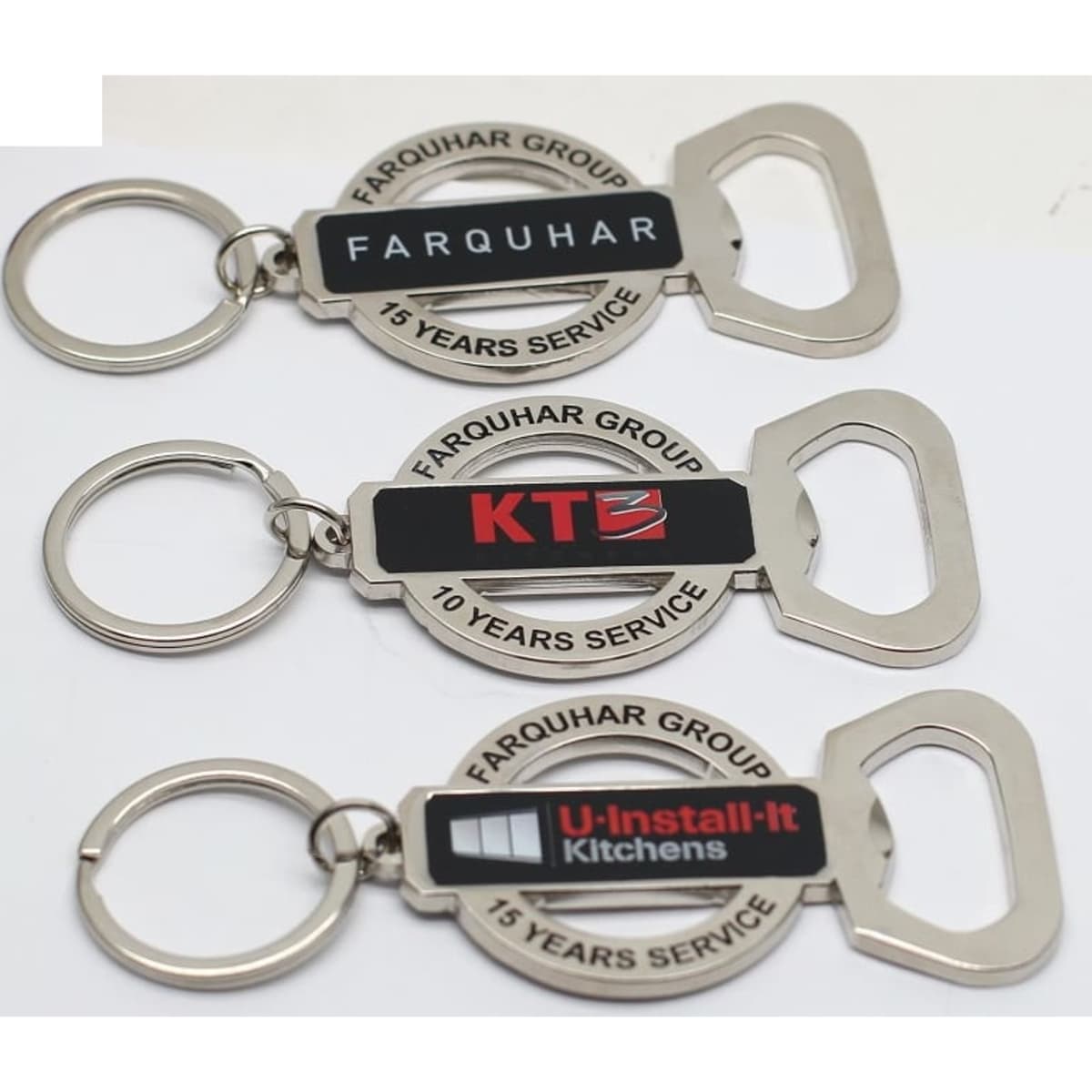 A drink bottle opener keychain set in silver with a circular design, featuring logos and varying text designs.