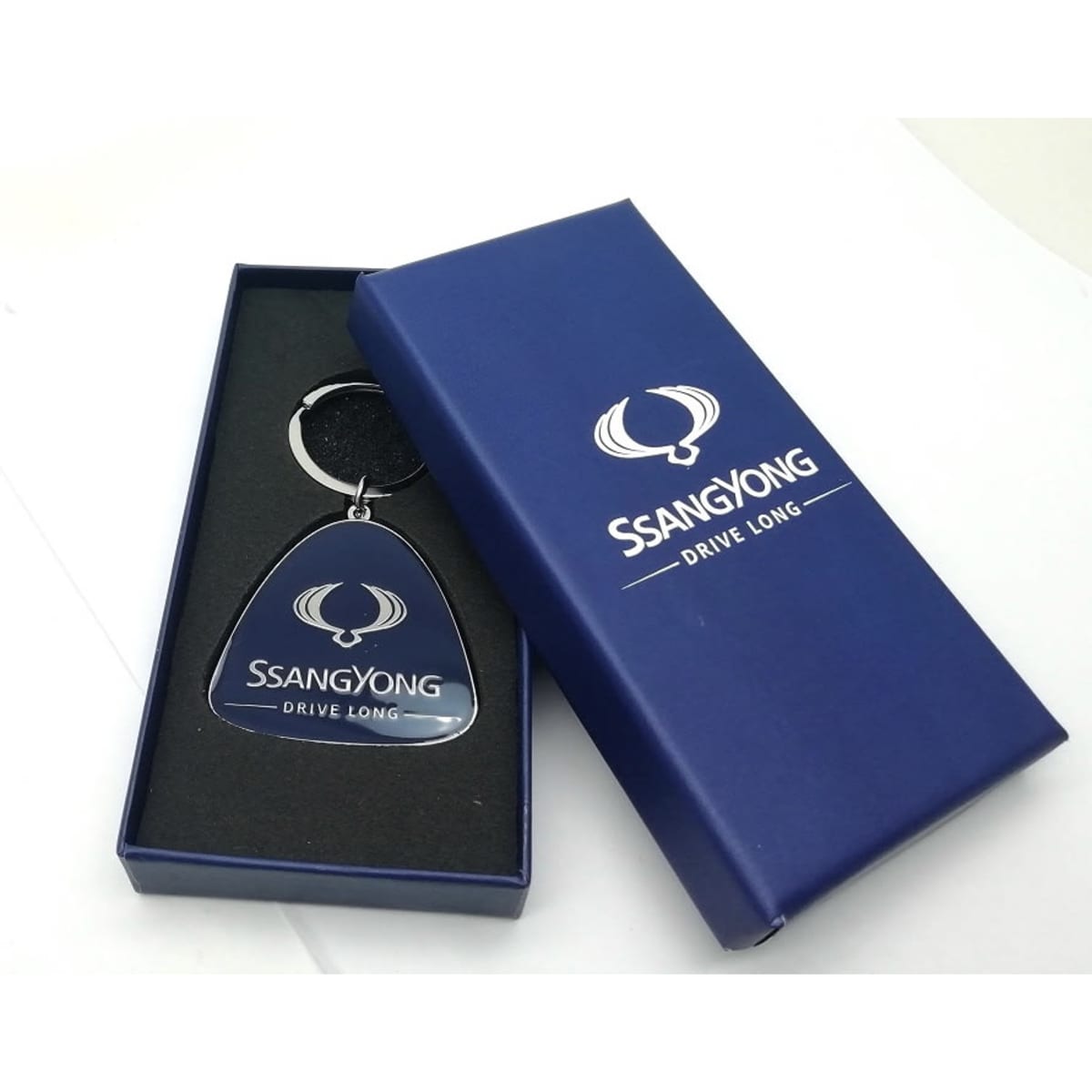 A keychain with a dark blue and silver tag, displayed in a dark blue box with a logo and branding.