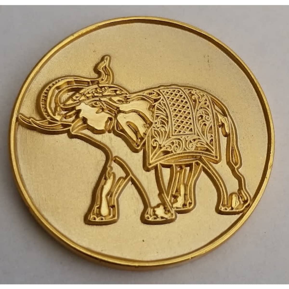 A gold lapel pin featuring an intricately designed elephant. The pin has a shiny gold finish.