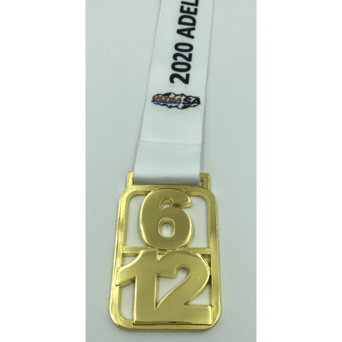 A gold medal with a white ribbon, featuring the numbers 6 and 12, and a logo.
