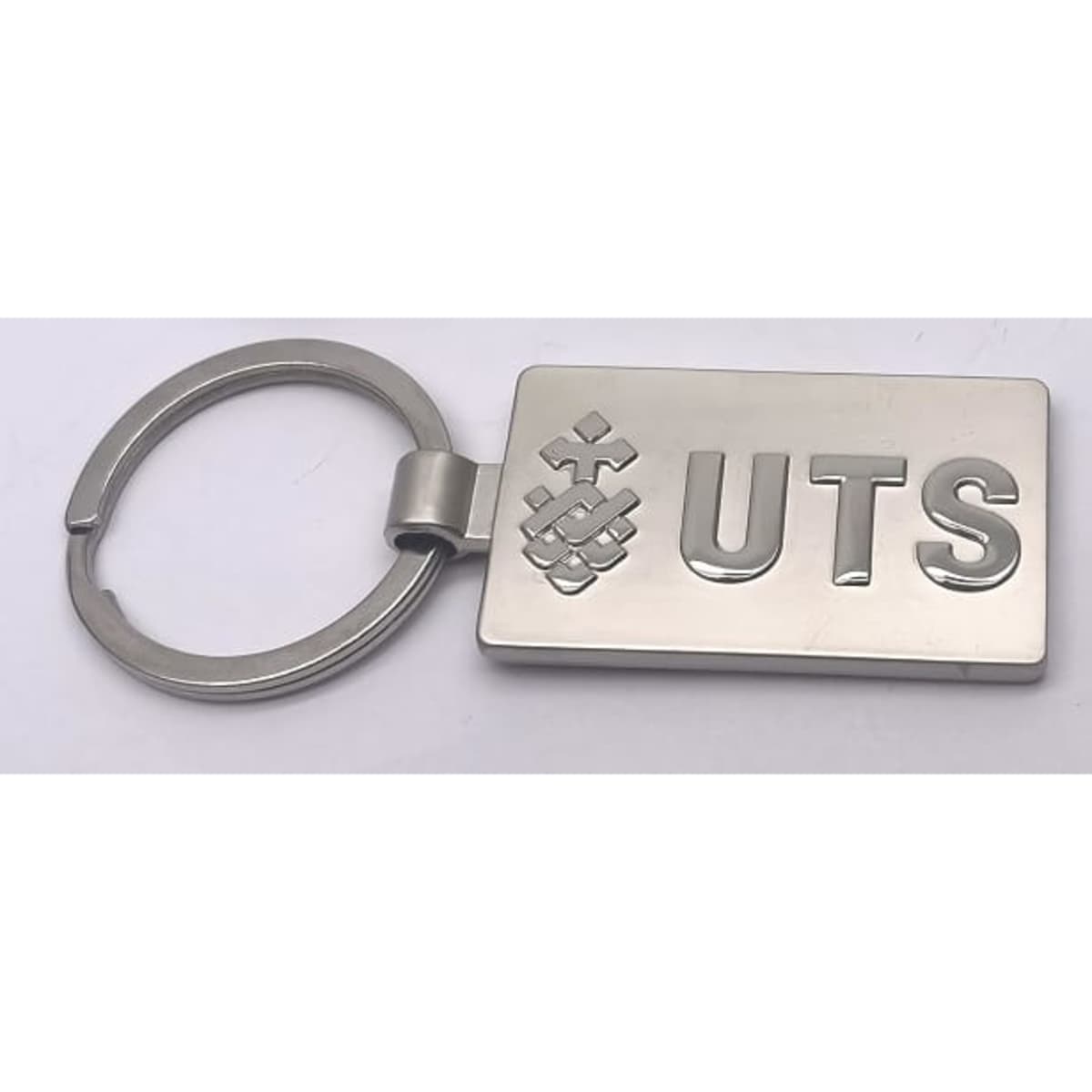 A silver keyring featuring a rectangular shape with a logo and the letters "UTS."