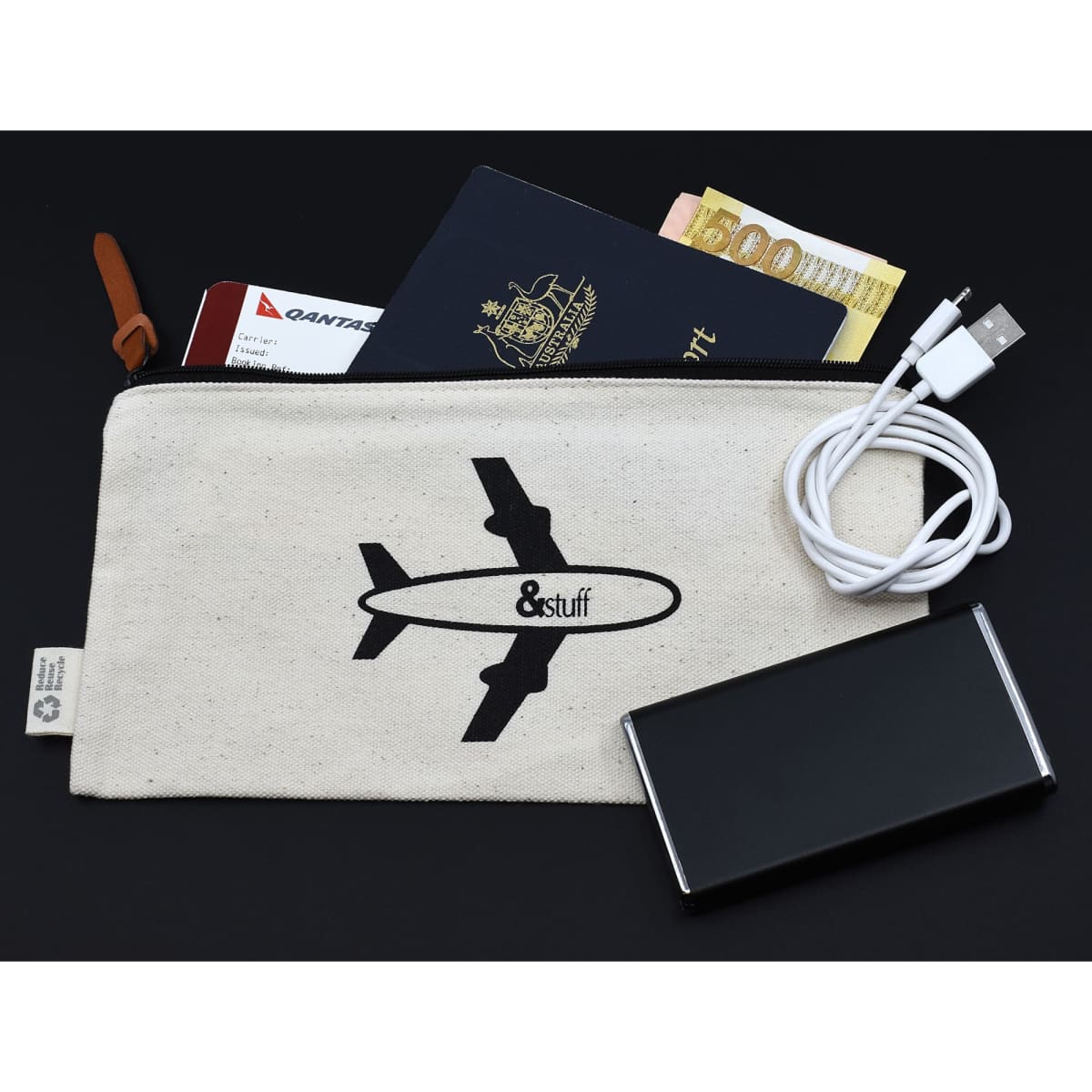 A calico travel pouch featuring an airplane design, containing a passport, cash, and charging cables.
