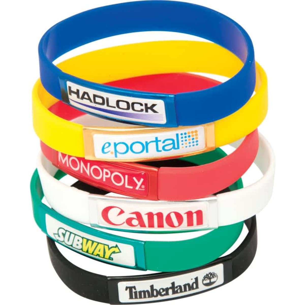 A stack of silicone wristbands in various colours, featuring different logos and branding on each band.