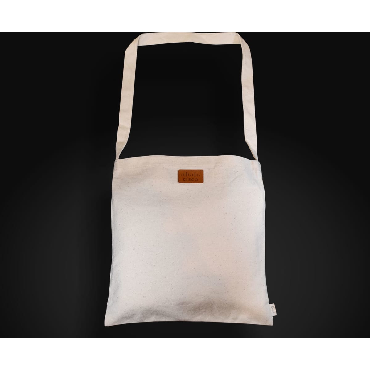 A light-coloured, long-handled shoulder bag with a logo on the front, featuring a simple, minimal design.