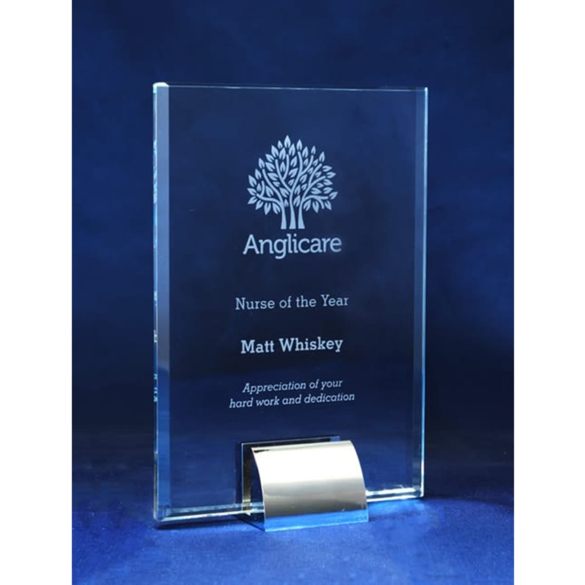 A glass award featuring a decorative tree design, with engraved text honouring "Nurse of the Year" and a name.