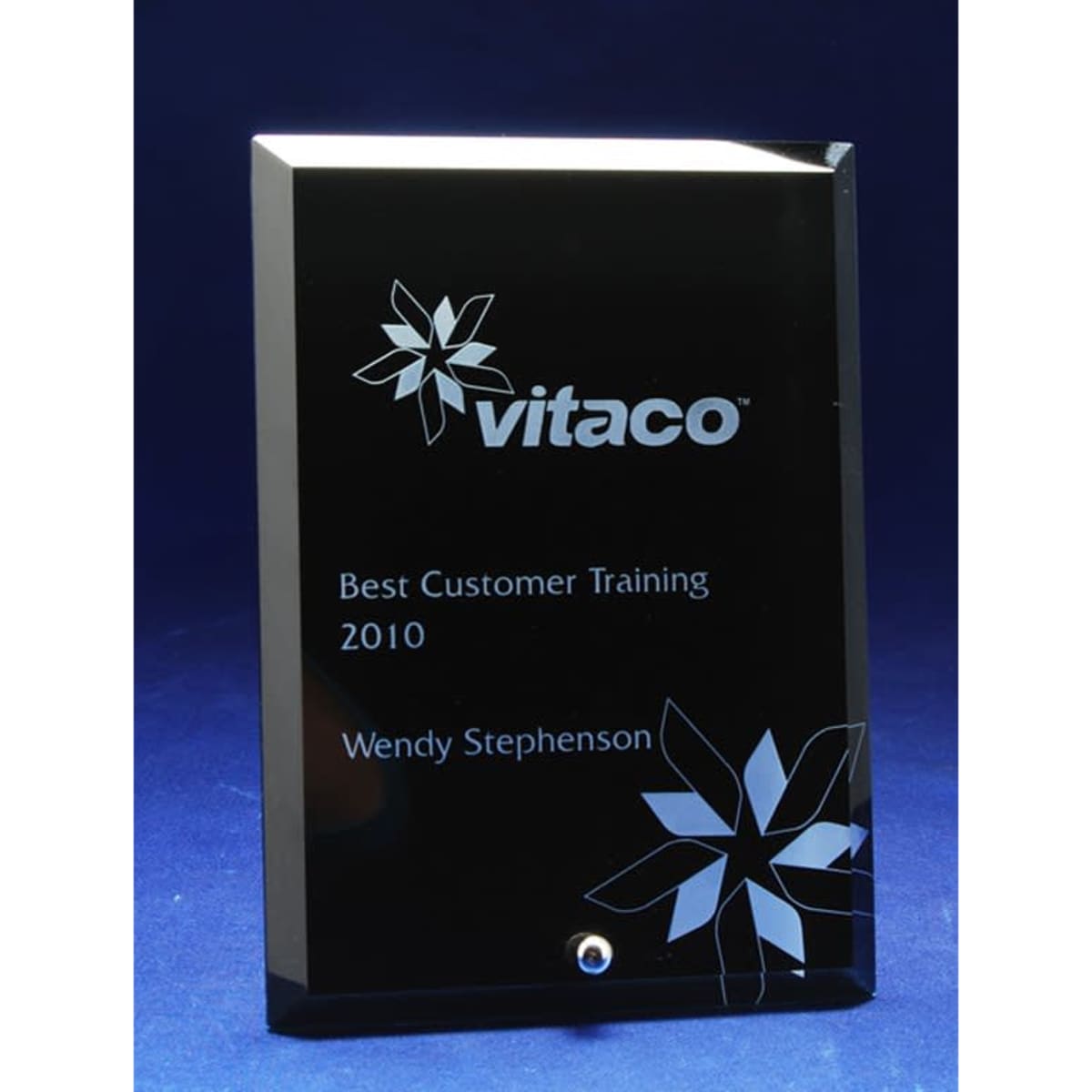 A glass rectangle award with a glossy black surface, featuring a floral design and laser engraving.