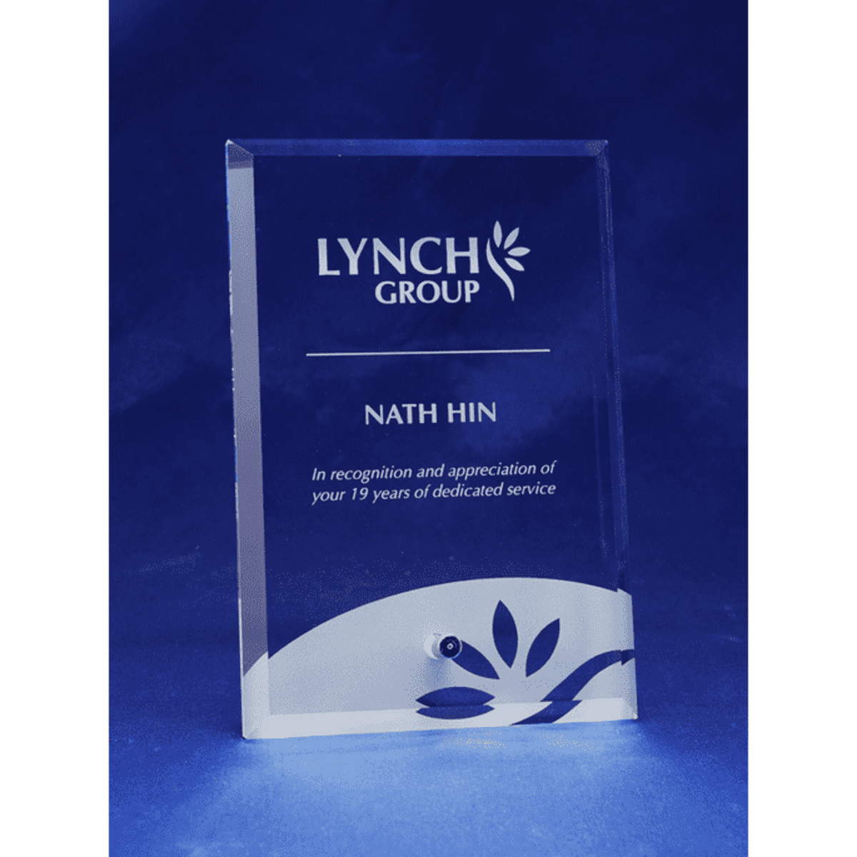 A clear glass rectangular award with a laser-engraved design and a logo at the top.