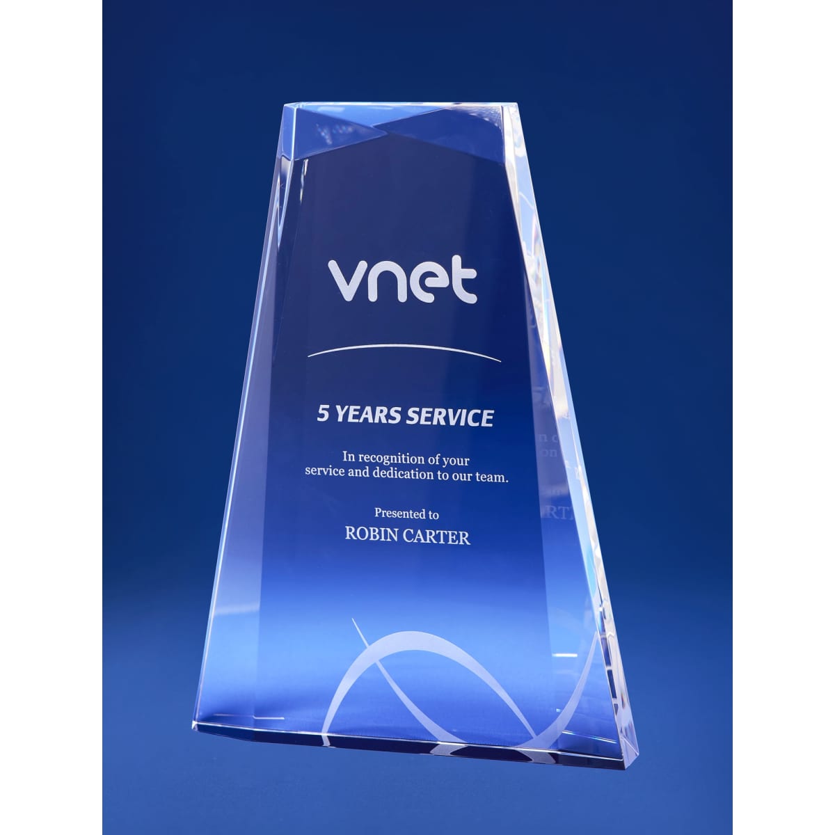A large crystal award with multiple facets, featuring a blue gradient and a logo, presented in a gift box.
