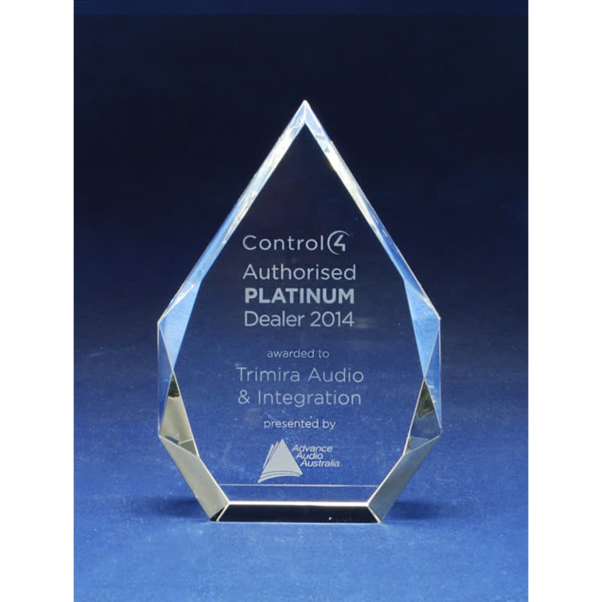 A crystal trophy in a pointed shape, featuring clear facets and engraved text on a blue background.