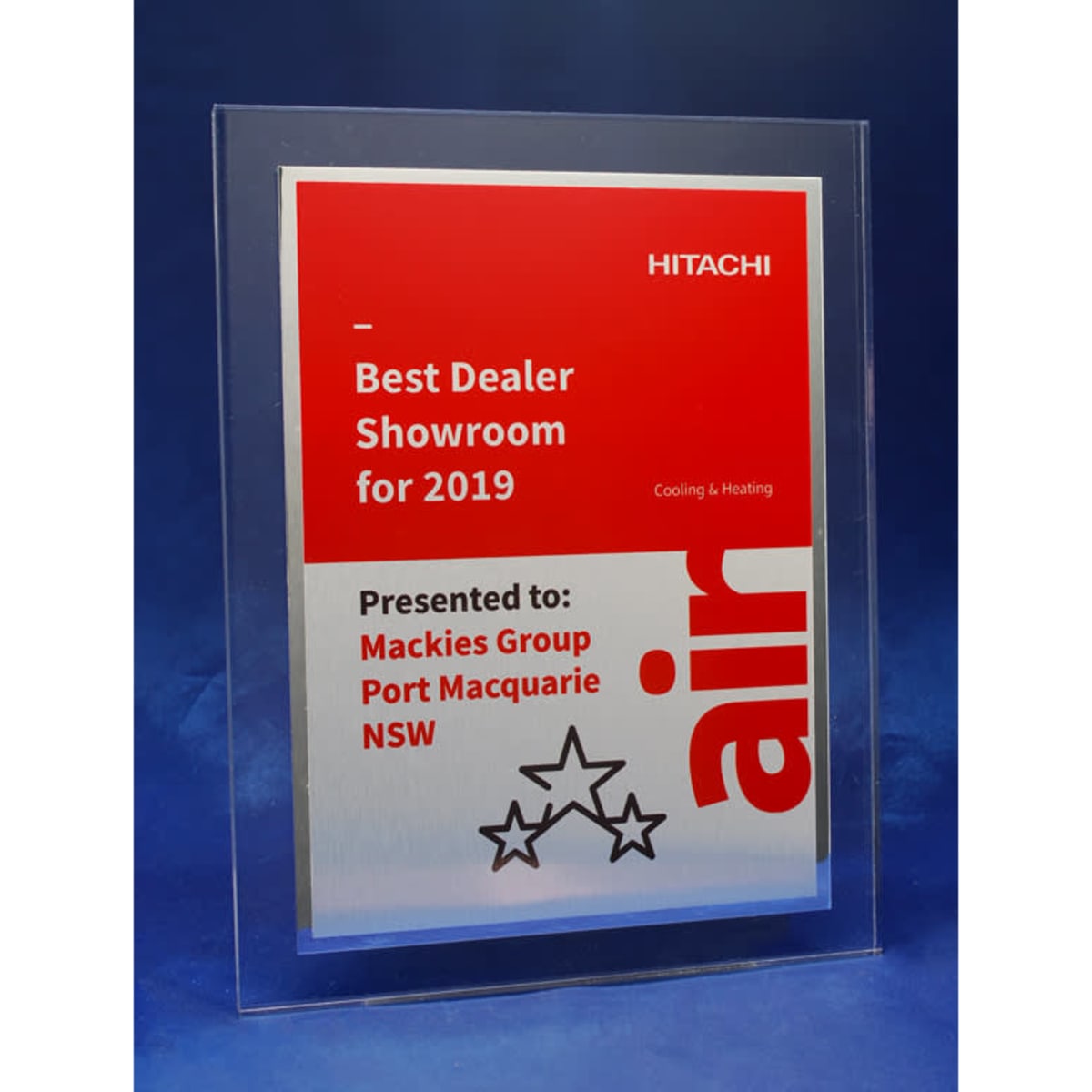 A clear acrylic plaque features a brushed metal plate with a shiny border and a logo. It has red and silver colouring.