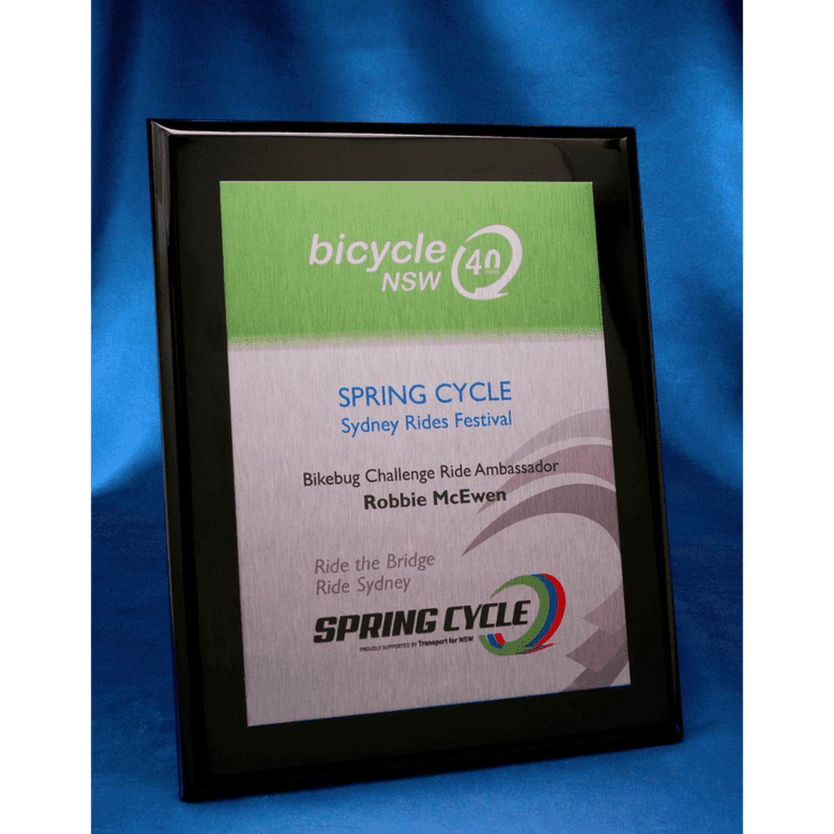 A black plaque with a brushed silver printed metal plate featuring a logo and promotional text.