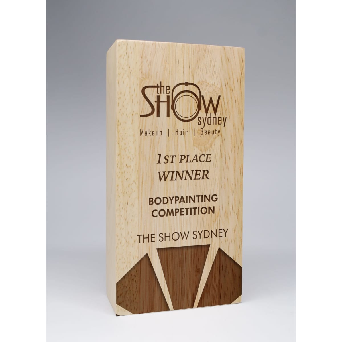 A wooden award in a light natural finish with angular design elements, featuring engraved text and a logo.