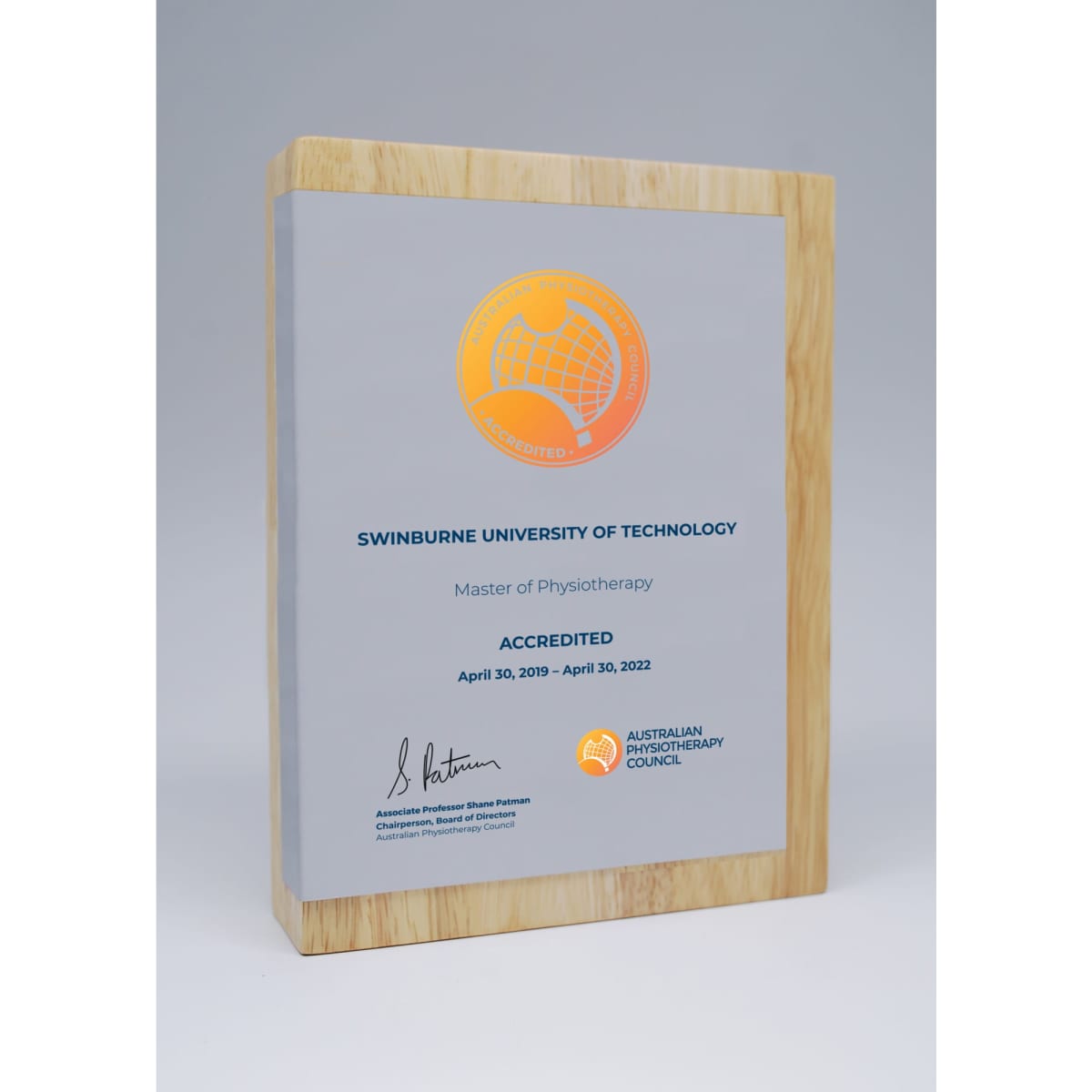 A wooden award featuring a printed metal plate, showcasing a silver and natural wood design.