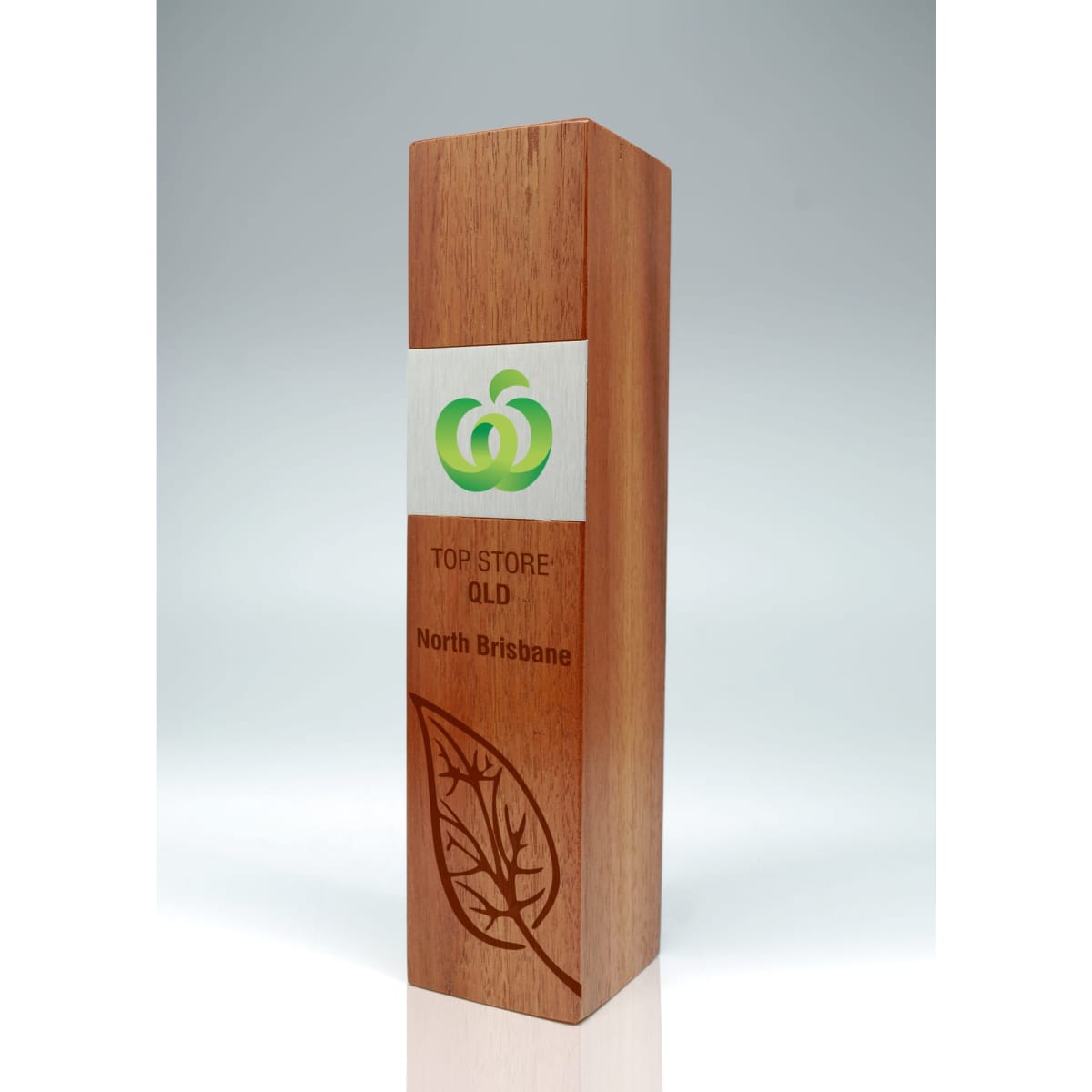A wooden trophy in shades of brown, featuring a silver panel with a logo and engraved text.