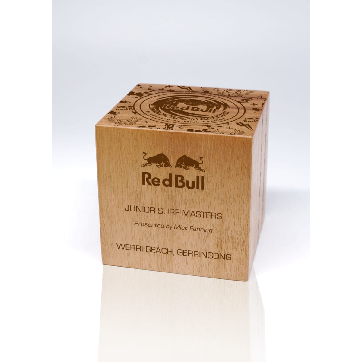 A wooden cube trophy with engraved details and a logo, featuring a natural finish.