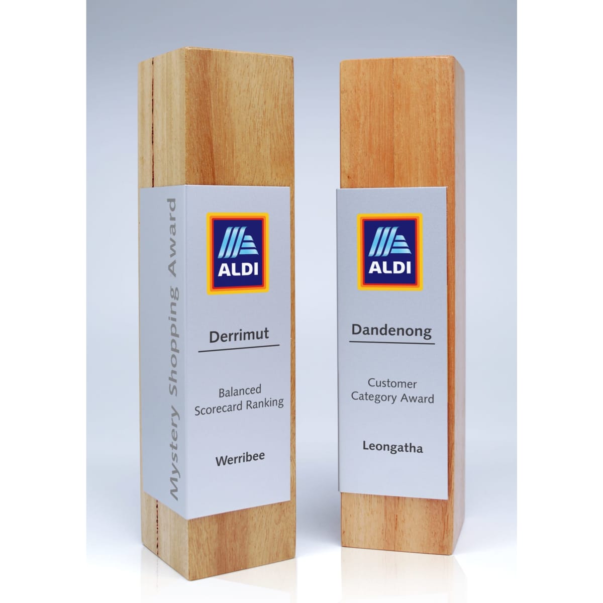 Two wooden trophies with metal wraps, one in light wood and the other in a darker wood, featuring branding.
