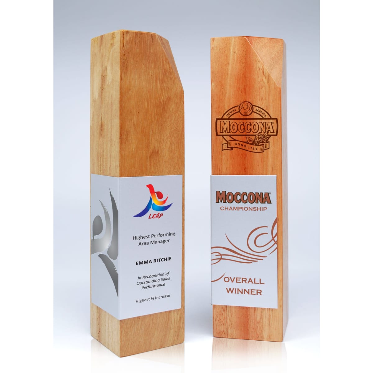 A wooden trophy with a polished finish, featuring metal accents and engraved text on both sides.