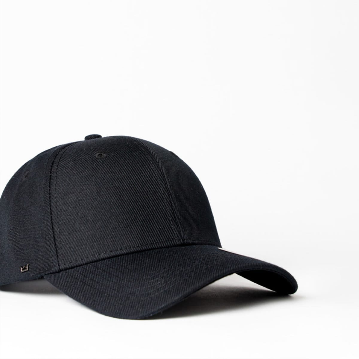 A black six-panel snapback cap featuring a curved brim and a logo on the side. Suitable for kids.