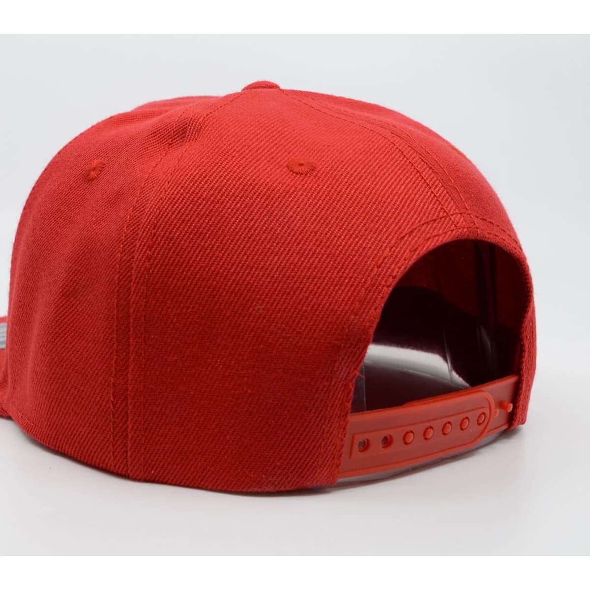 A red snapback cap showcasing the back design and adjustable strap. The cap features a logo on the side.