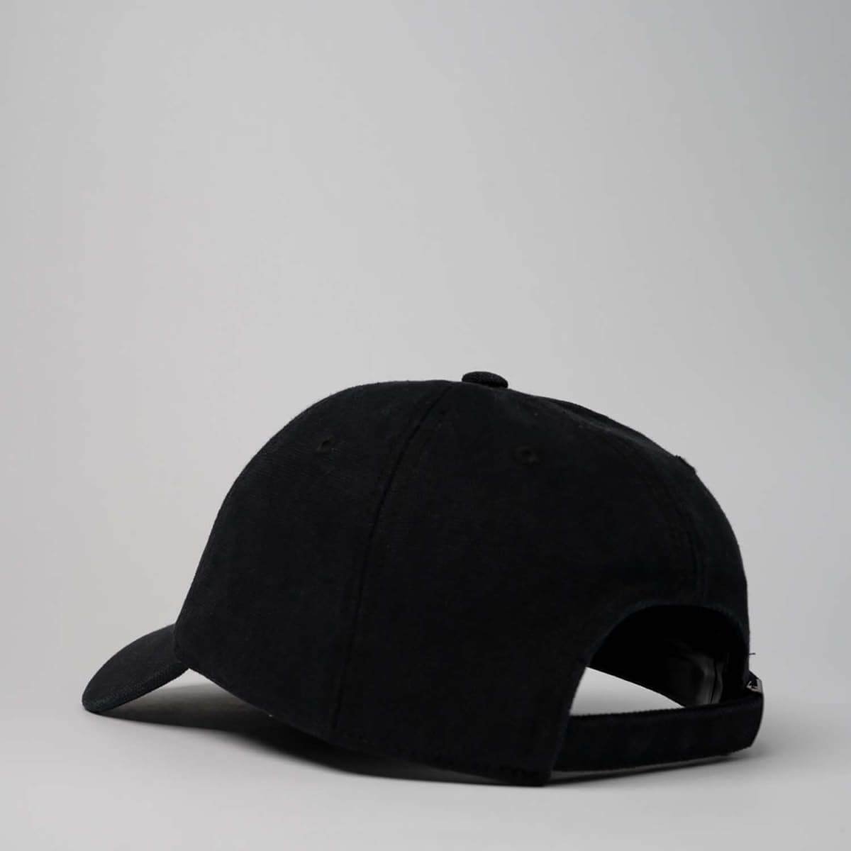 A black unstructured 6-panel cap featuring a rear adjustable strap and a logo on the side.