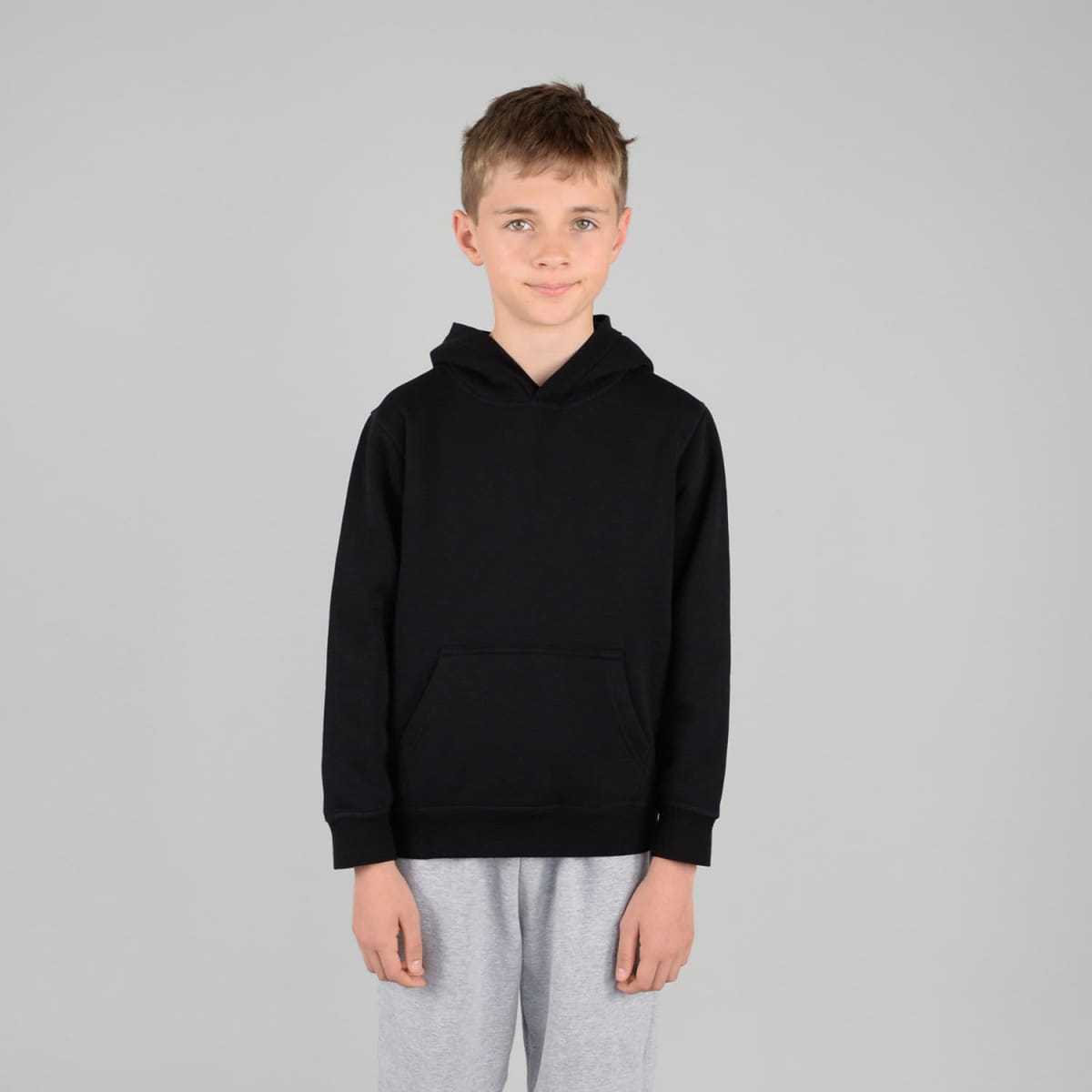 A black hoodie with a kangaroo pocket and a hood, worn by a child in grey sweatpants, set against a plain background.