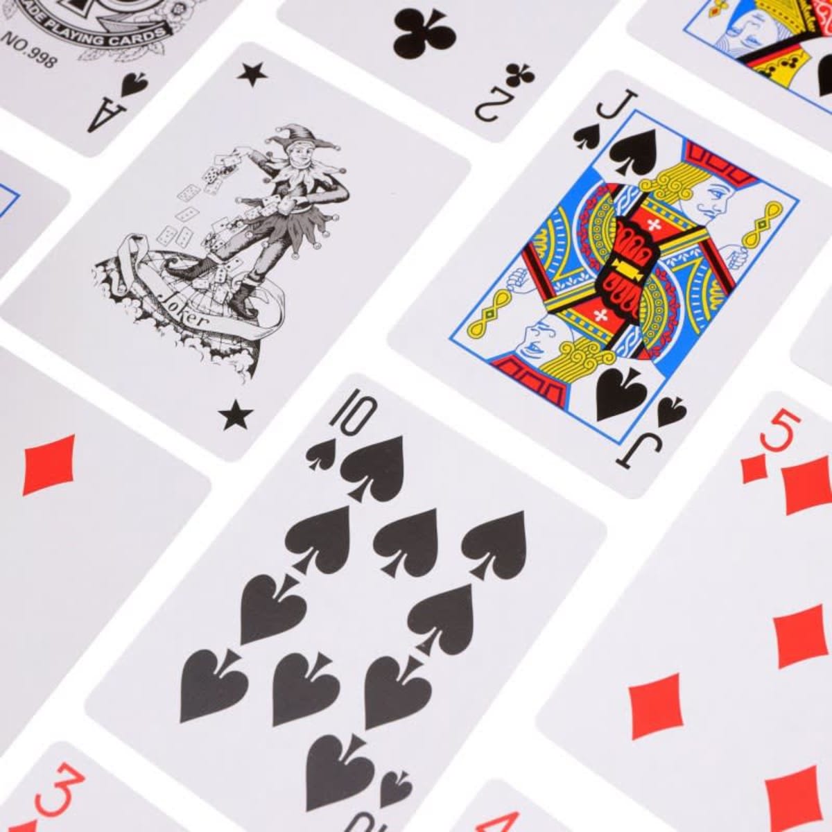 A set of playing cards featuring various designs and symbols in red, black, and multicoloured patterns.