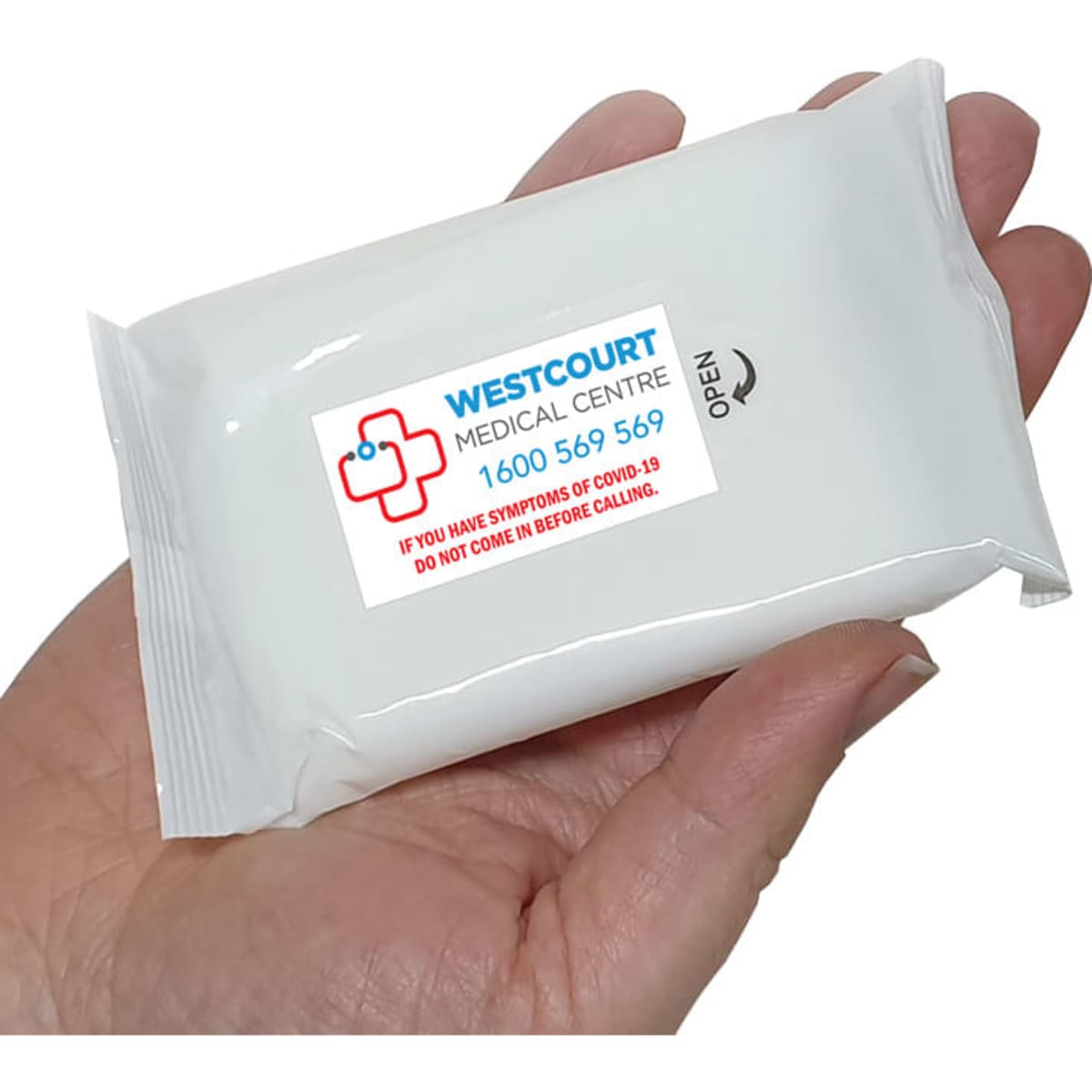 Alcohol wipes in a compact white packet, held in a hand, featuring a logo on the front.