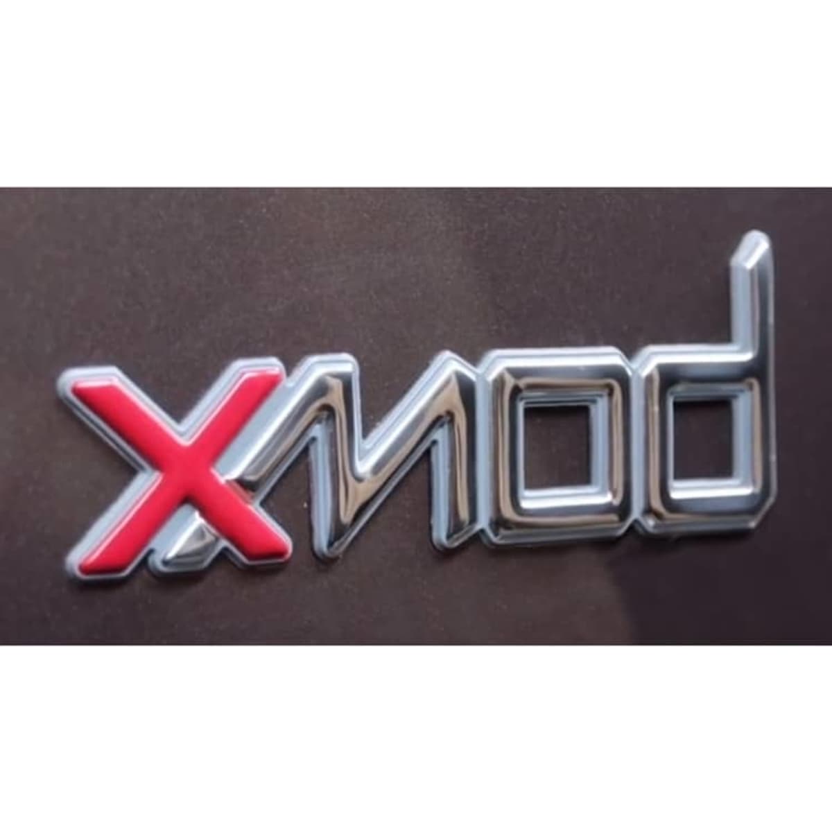 A glossy metallic logo featuring the text "Xmod" in silver and red on a dark background.