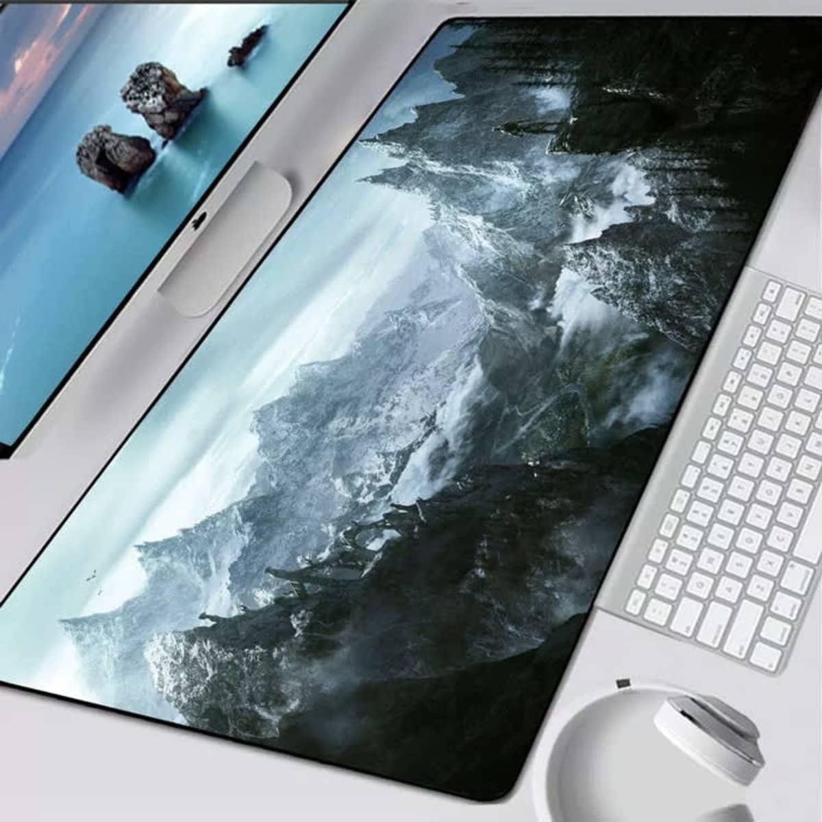 A large dark green and grey gaming mat featuring a mountainous landscape, positioned on a desk with a keyboard and mouse.