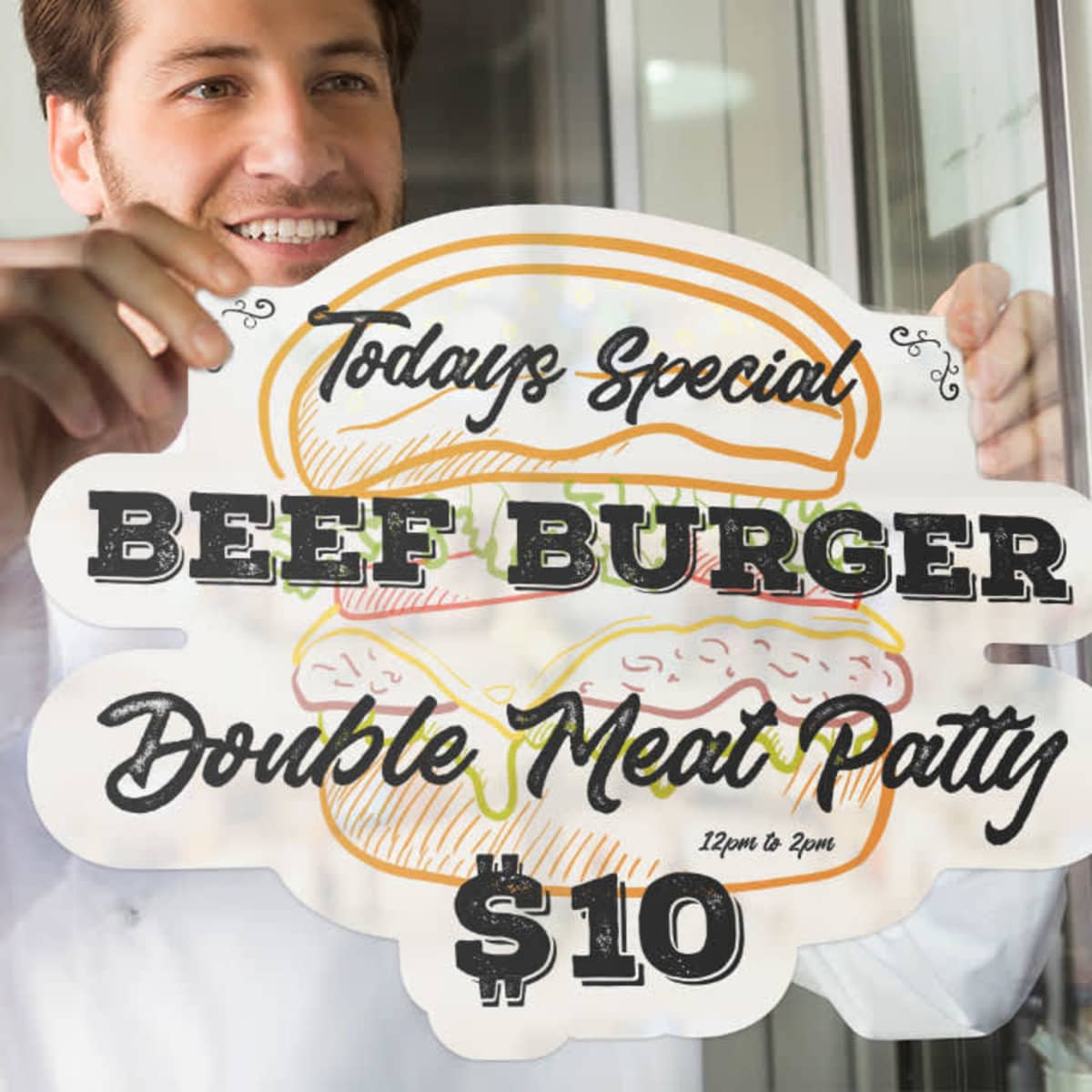 A person is placing a colourful static cling decal of a beef burger with text on a glass surface.