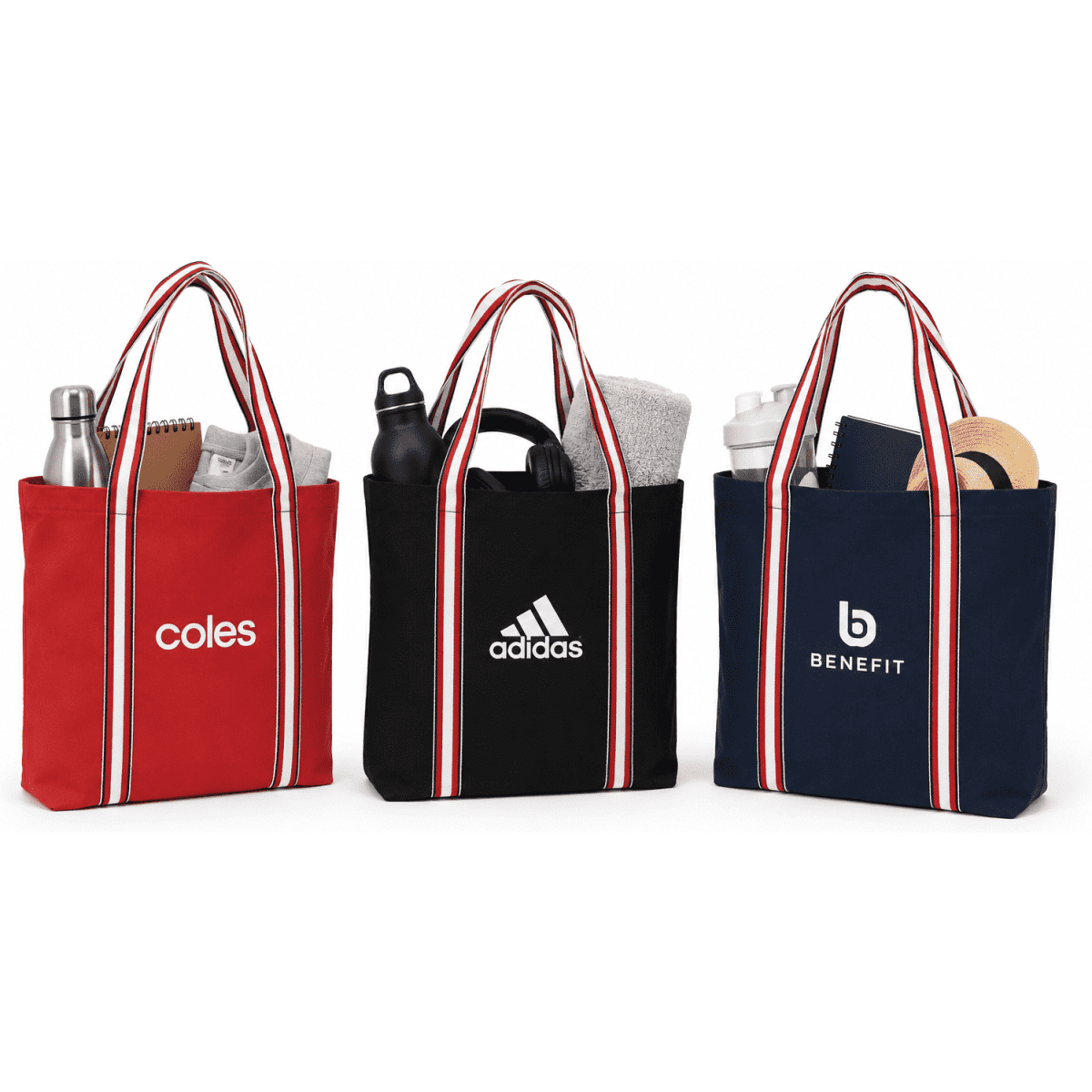 Three tote bags in red, black, and navy, each with striped handles and a logo, filled with various items.