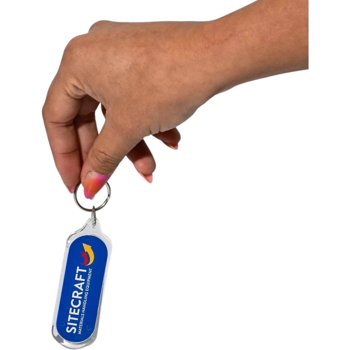 A hand holds an oval acrylic keychain with a silver metal ring and a blue logo on one side.